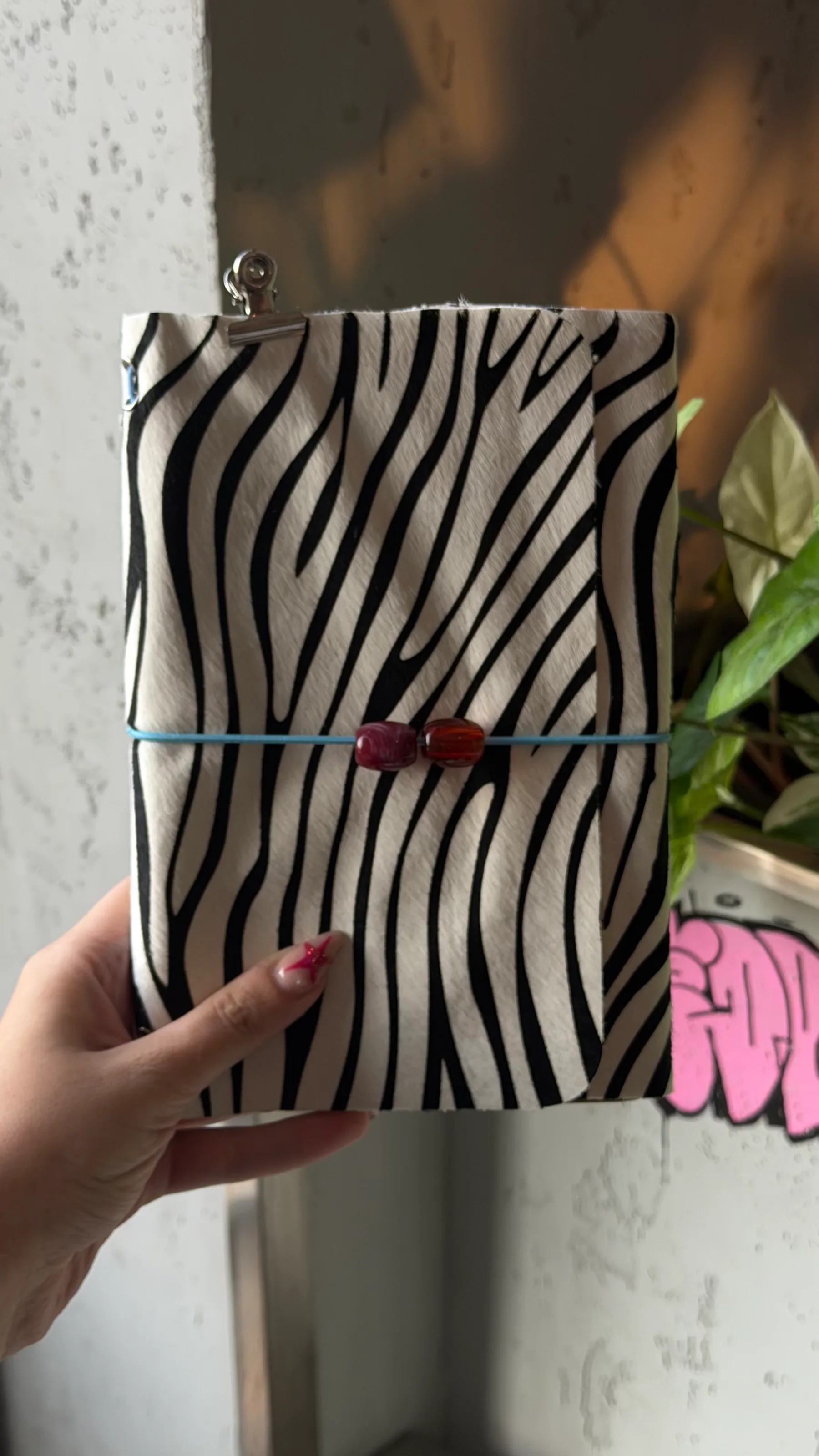 Zebra-striped journal with a blue cord and two decorative beads.